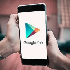 Person holding a smartphone displaying the Google Play logo